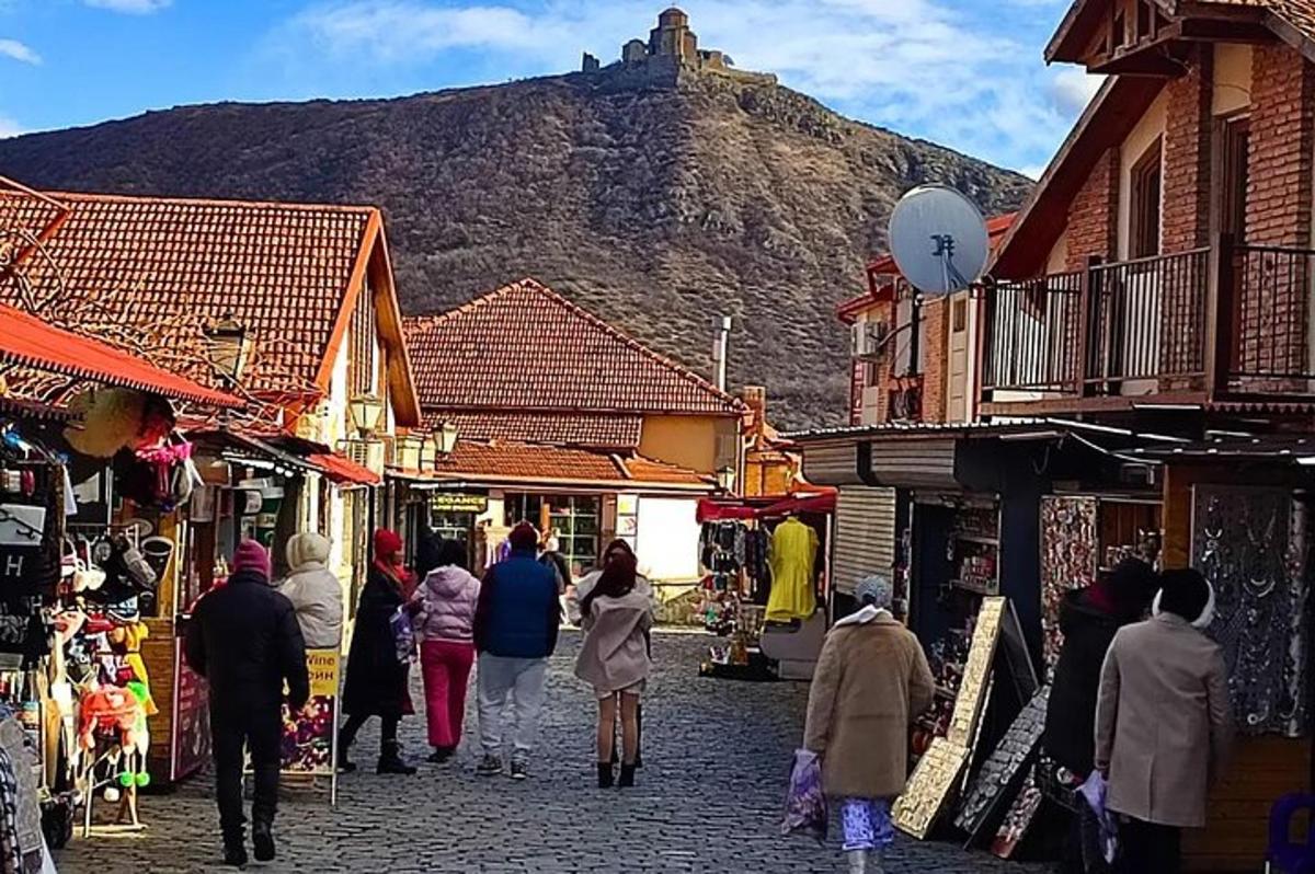 un grup de persones caminant per un carrer amb una muntanya al fons