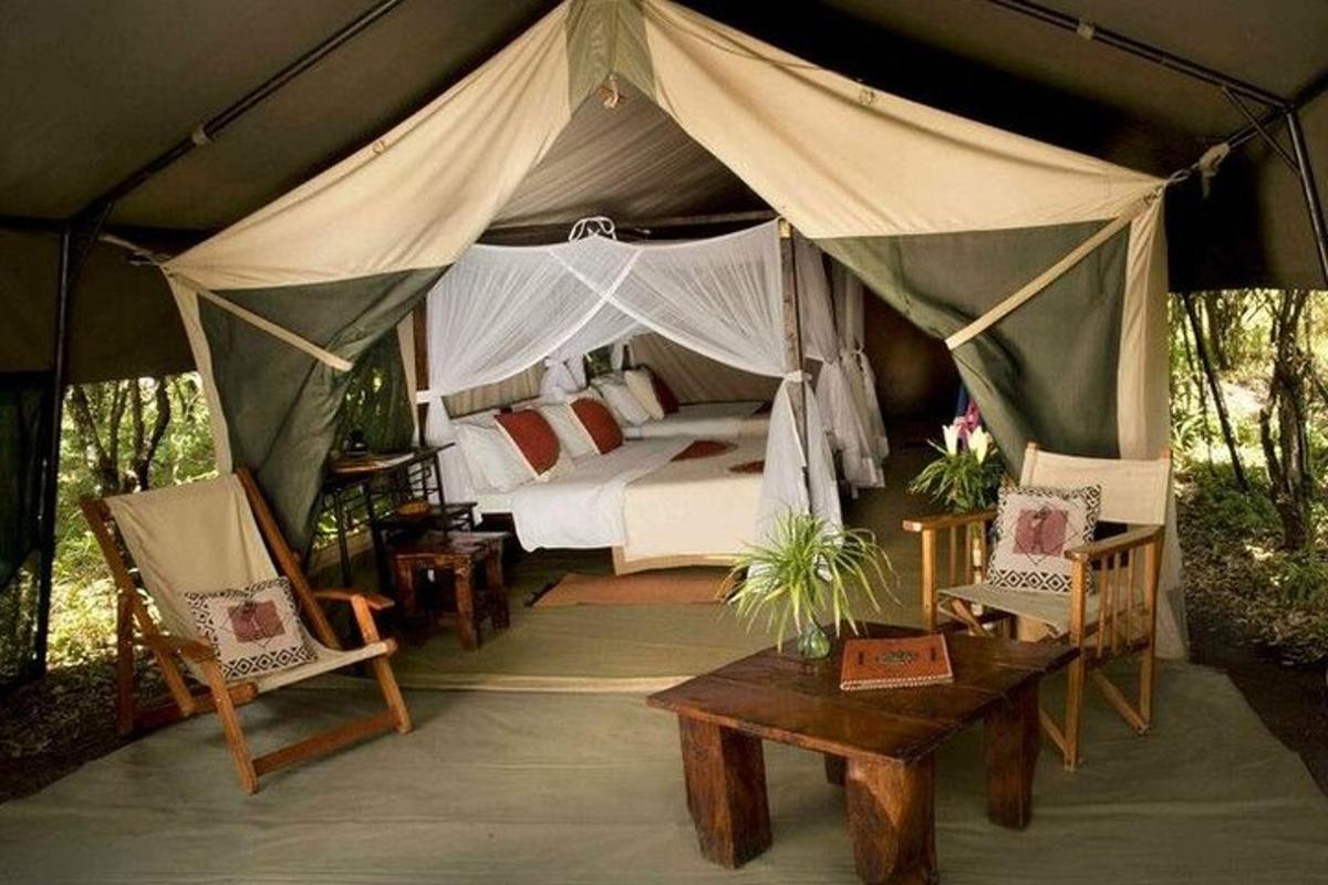uma tenda com uma cama, duas cadeiras e uma mesa