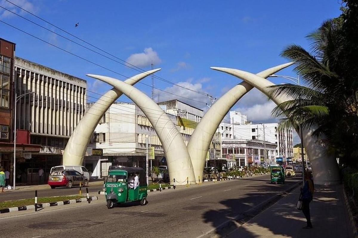 o mașină verde care circulă pe o stradă a orașului cu o sculptură