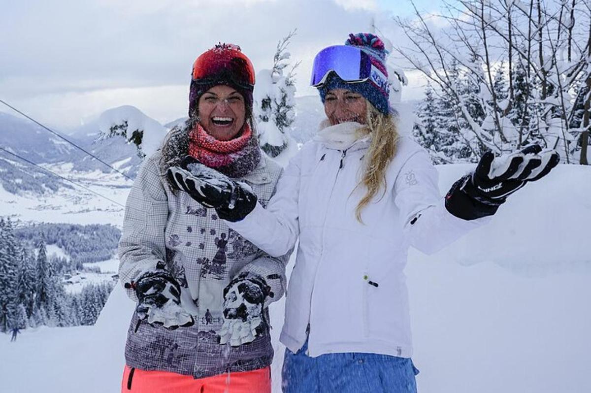 Dos personas paradas en la nieve con las manos en alto