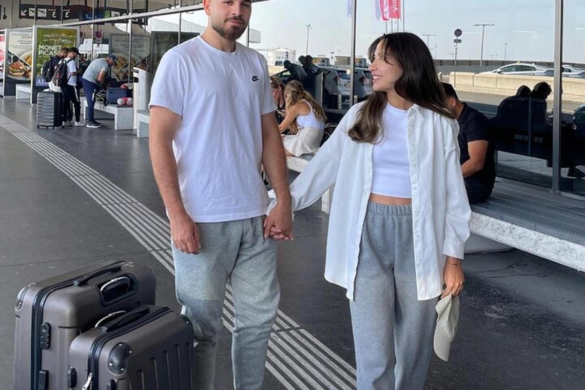 Un hombre y una mujer de pie en un aeropuerto con equipaje.