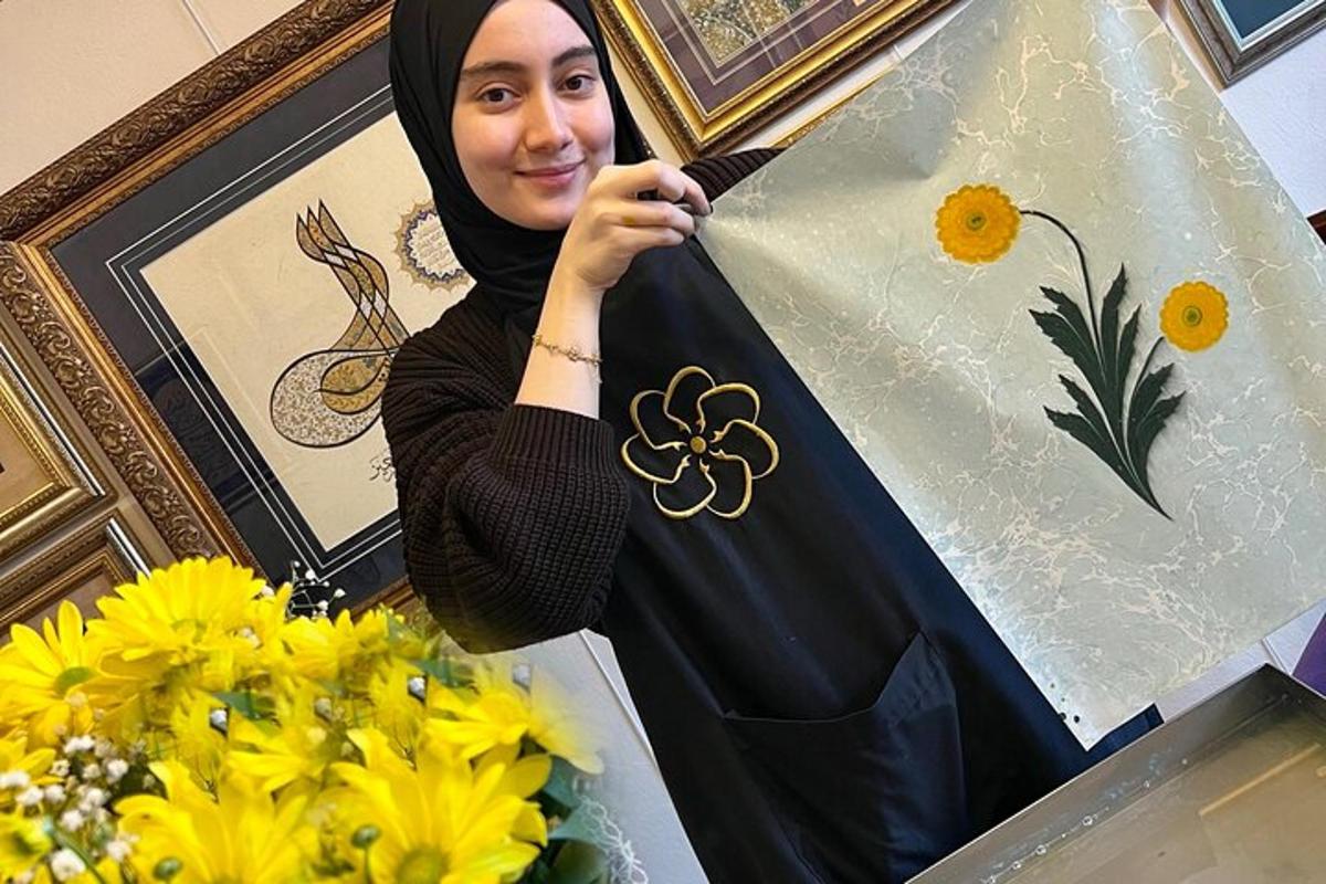 seorang wanita berhijab memegang layang-layang di samping bunga
