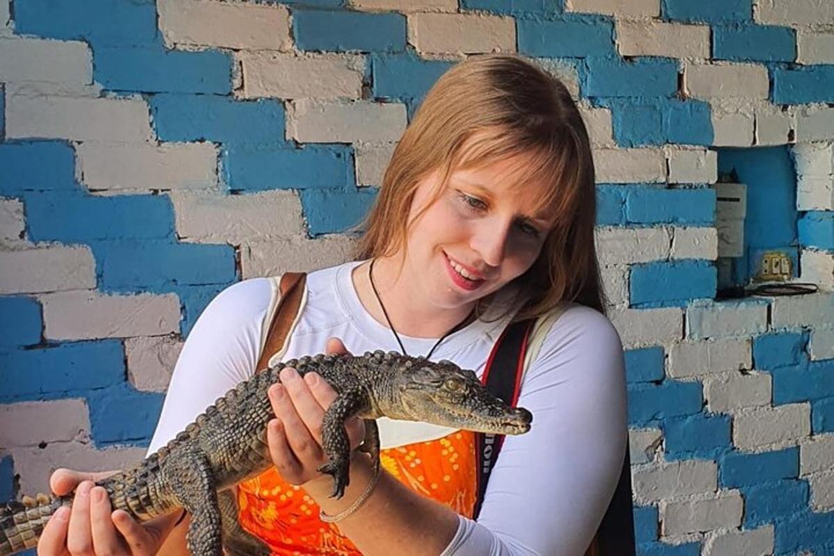 una dona que sosté un caiman davant d'una paret