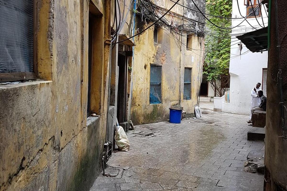 زقاق فيه مبنى قديم ورجل يجلس على مقعد