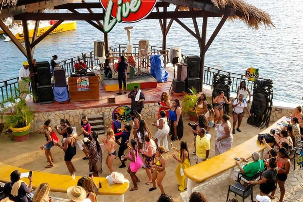 um grupo de pessoas dançando em uma festa perto da água