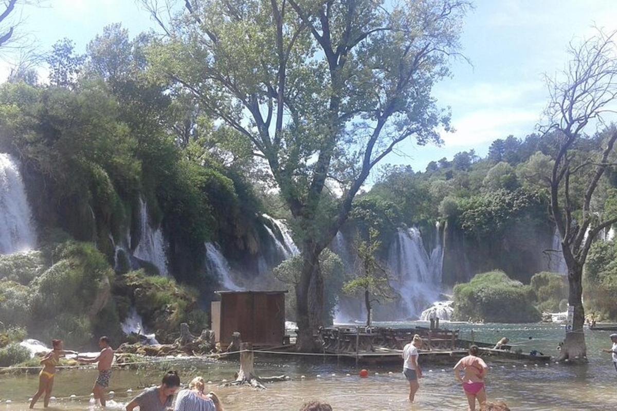 люди стоять у воді перед водоспадом