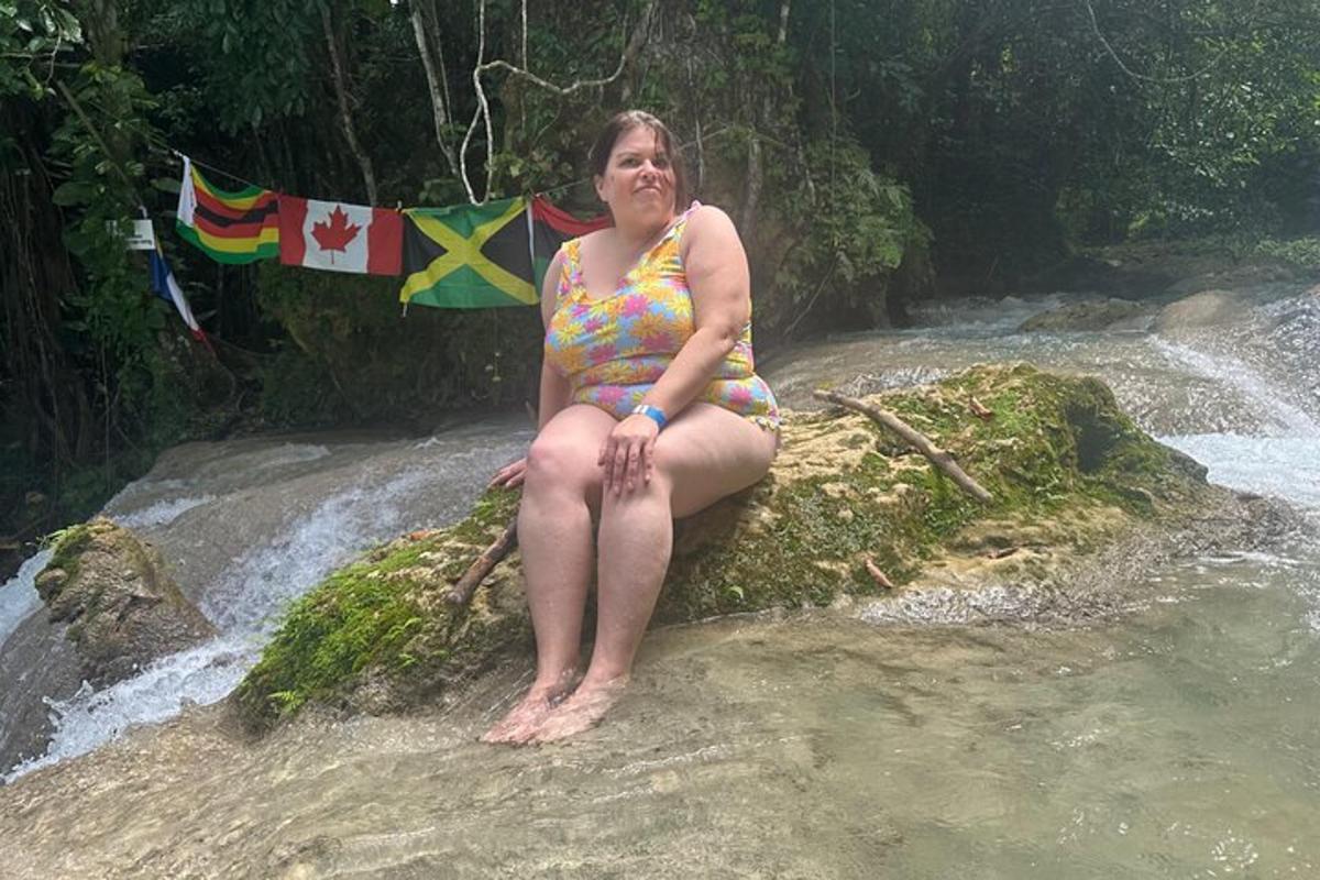 žena v plavkách sedící na skále v řece