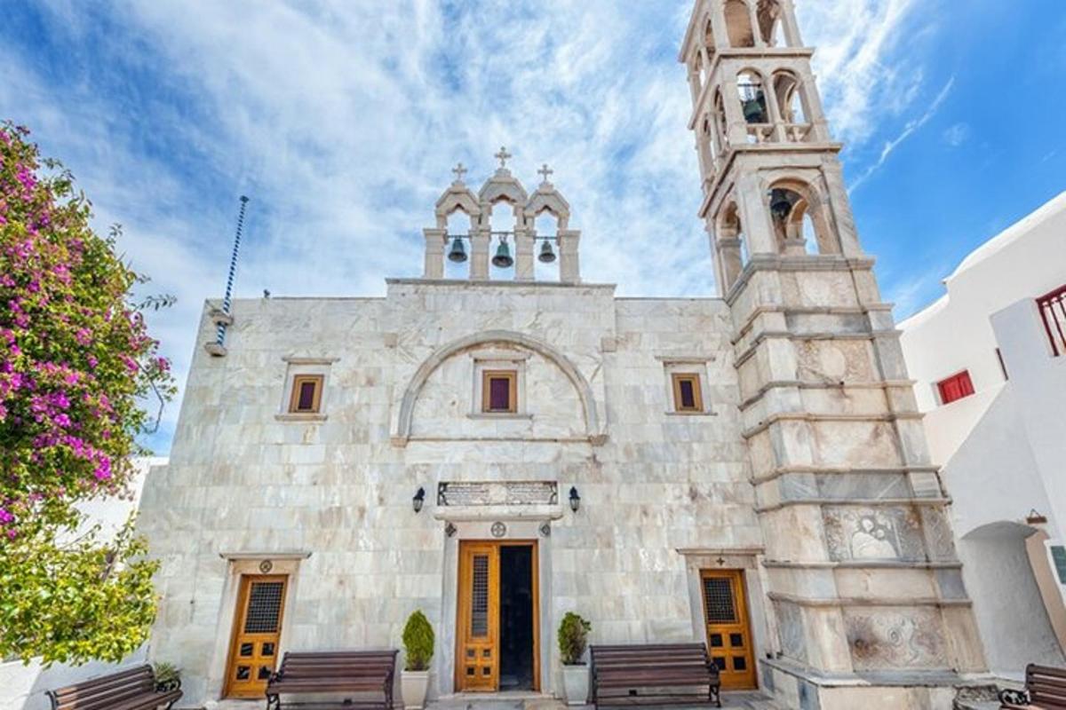 una chiesa con una torre dell'orologio e panchine di fronte