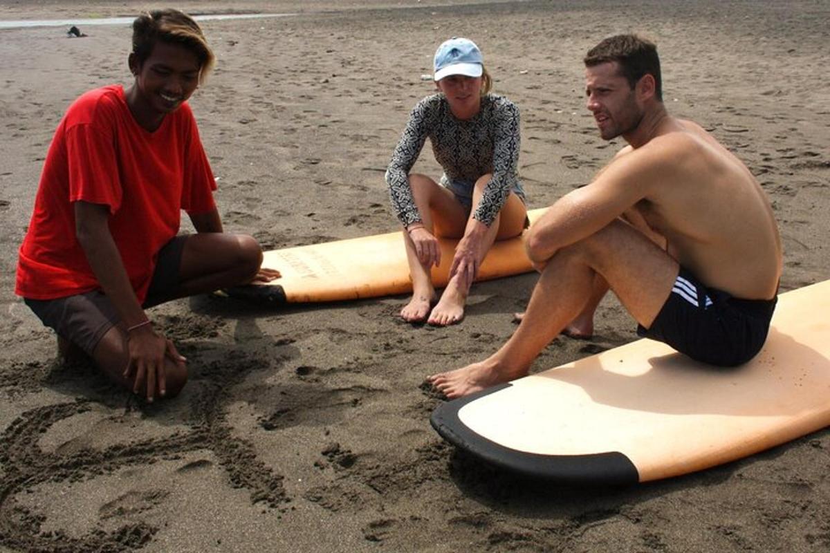 three people sitting on surfboards on the beach