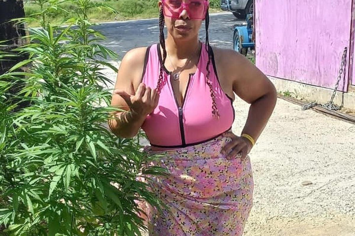 uma mulher com uma blusa rosa em pé ao lado de uma planta
