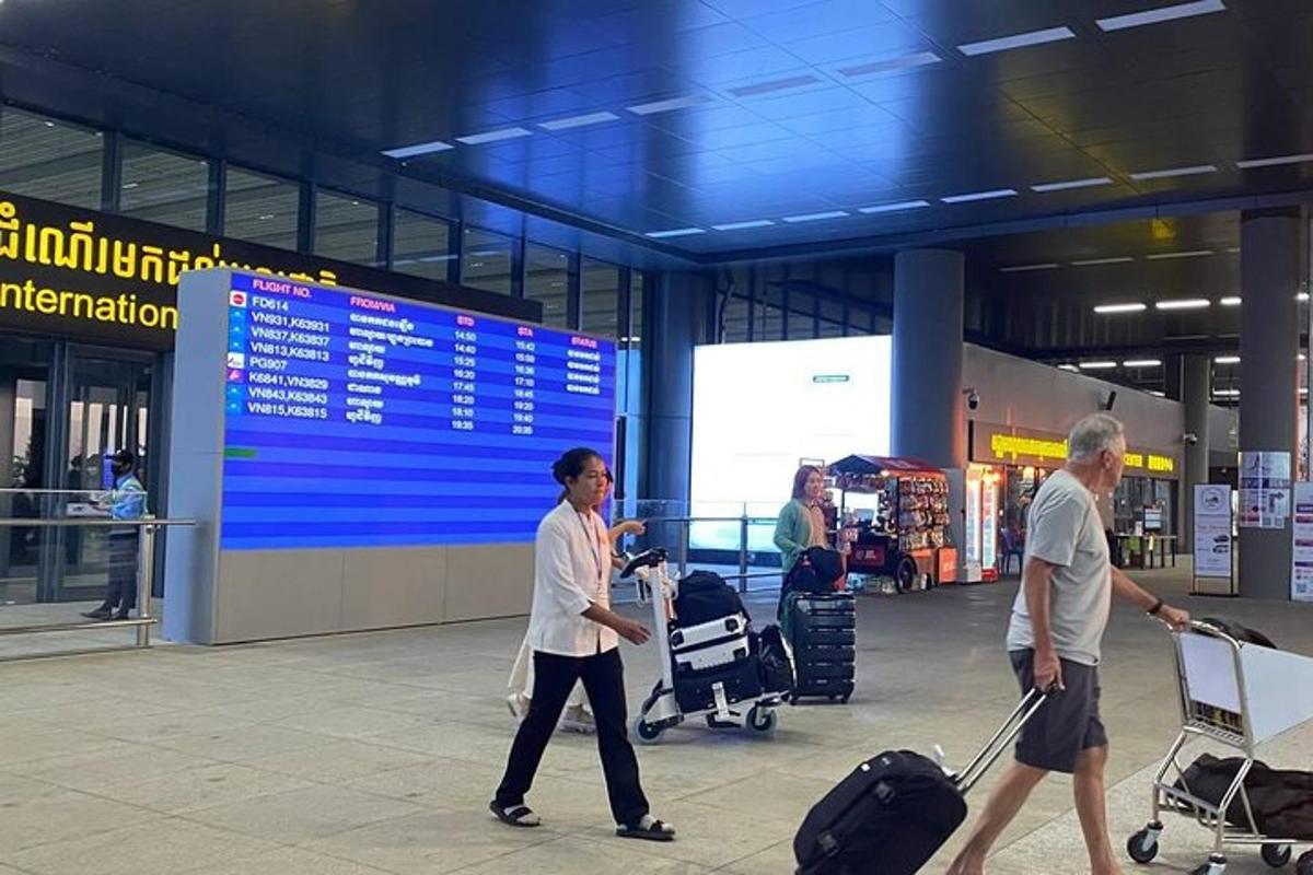 двоје људи шетају аеродромом са својим пртљагом