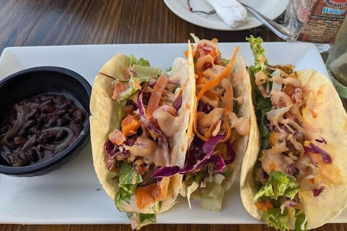 un plat blanc amb dos tacos i un bol de salses