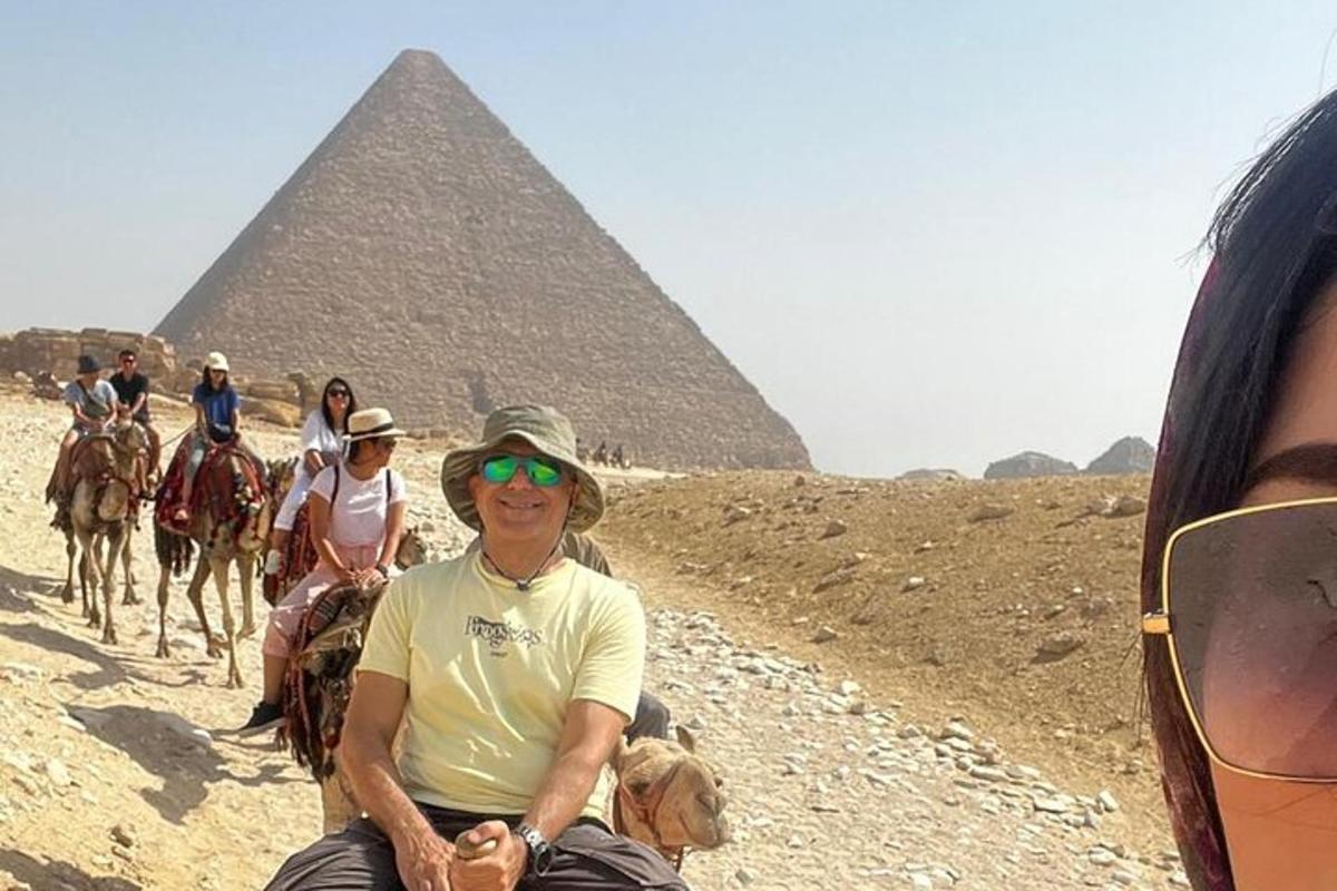 Skupina lidí na koních před pyramidami