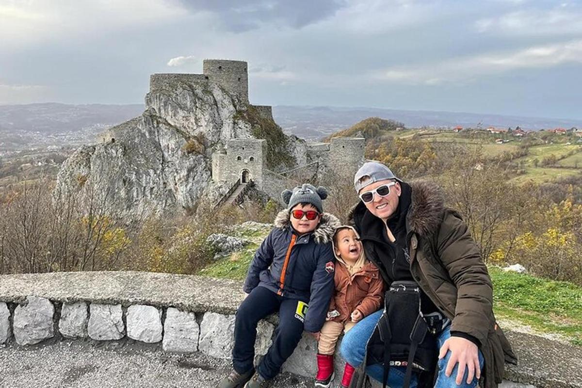 a woman and two children sitting on a wall with a castle