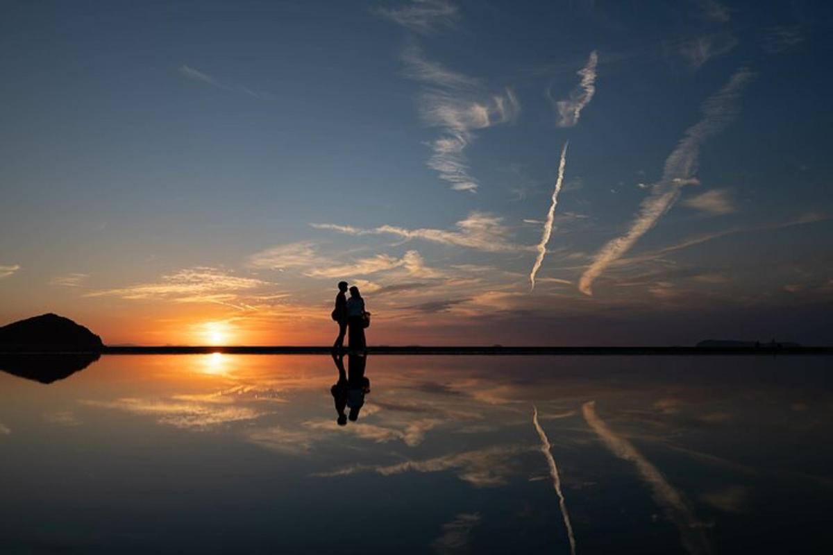a person standing on a body of water with the sunset