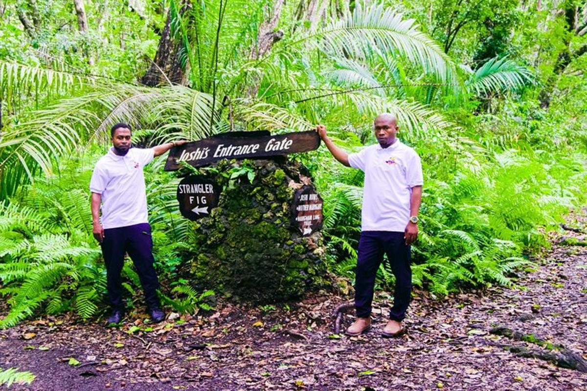 two men standing next to a sign in a forest