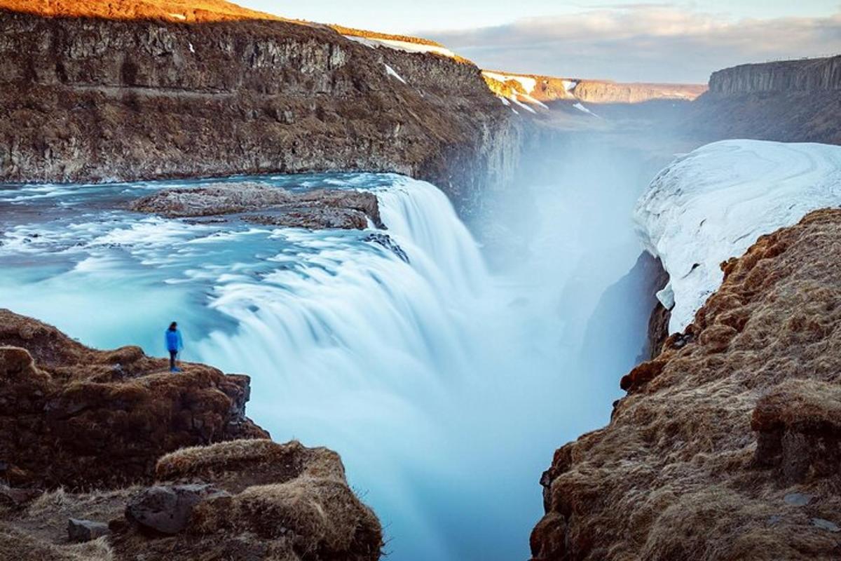 maður stendur á kletti við foss
