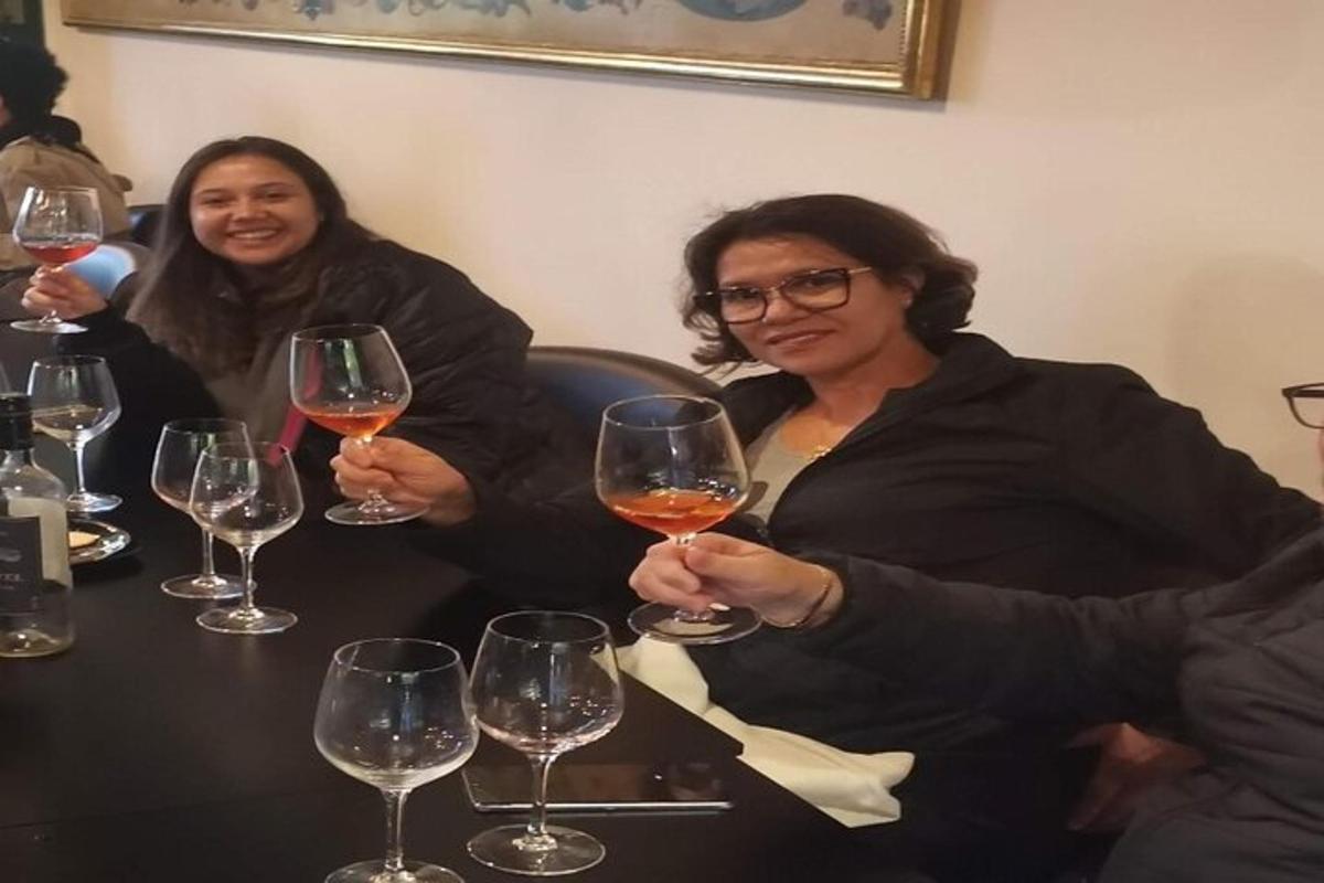 dve ženski, ki sedita za mizo in držita kozarce za vino