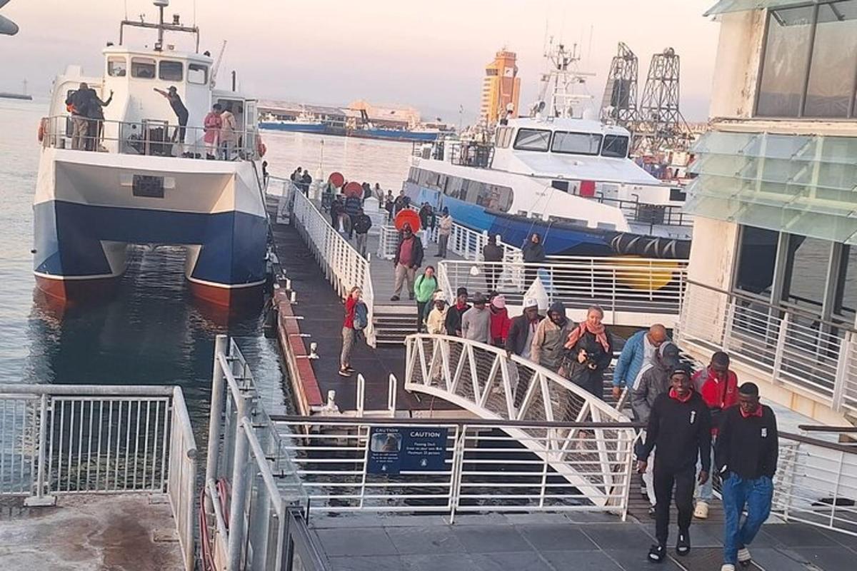 un grup de persones caminant per un moll a prop de dos vaixells