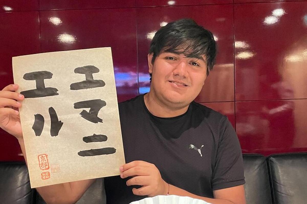Muž drží v ruke ceduľu s japonskými písmenami