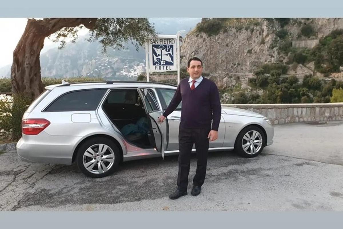 ein Mann im Anzug steht neben einem Auto