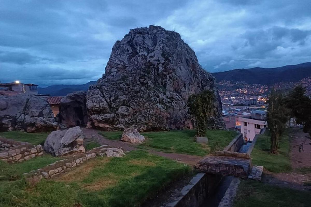 Una gran roca situada encima de un campo verde.
