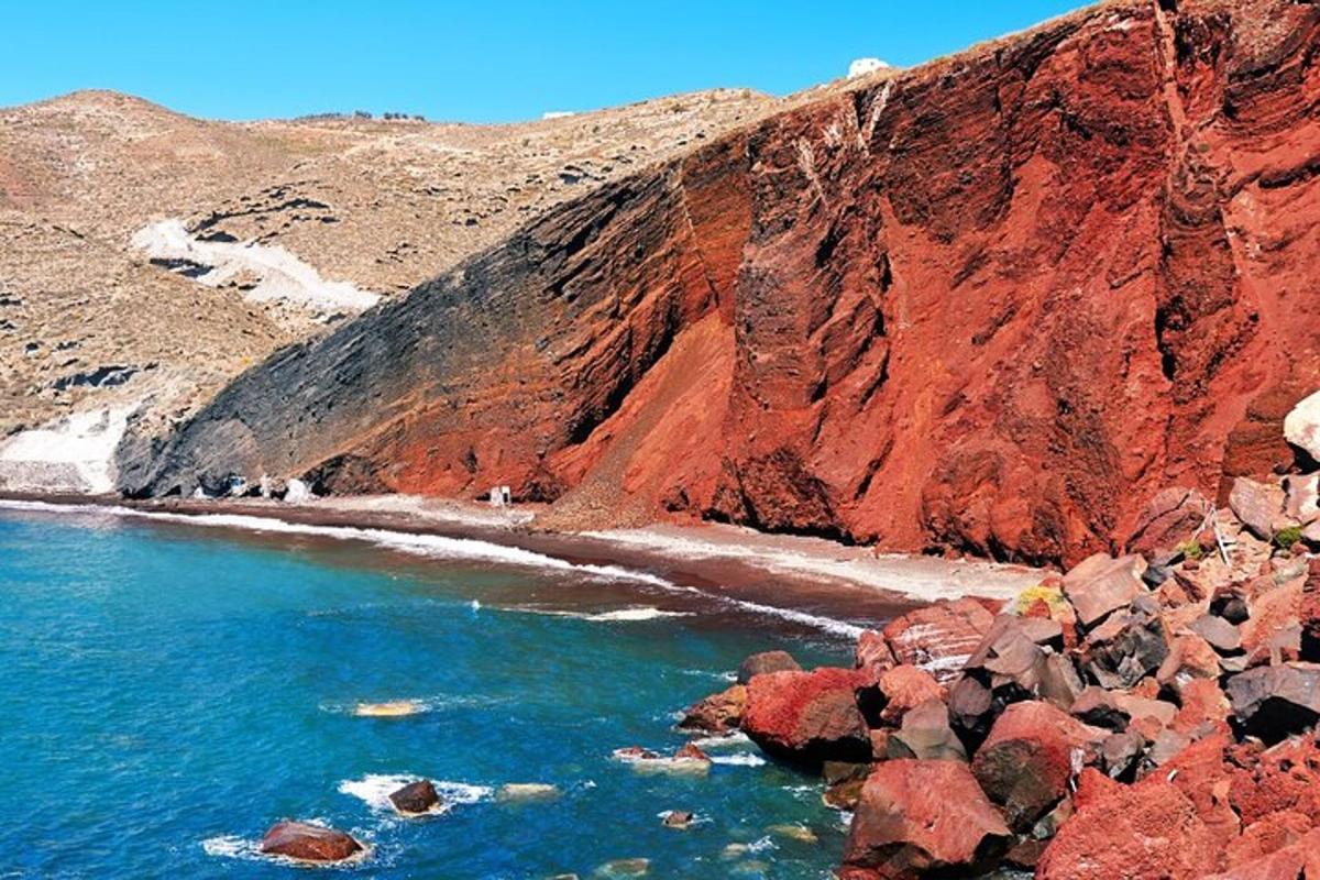 a beach with red rocks and the ocean