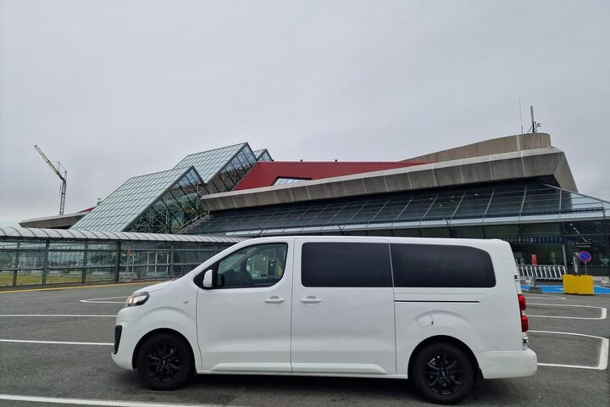 uma van branca estacionada em um estacionamento em frente a um prédio
