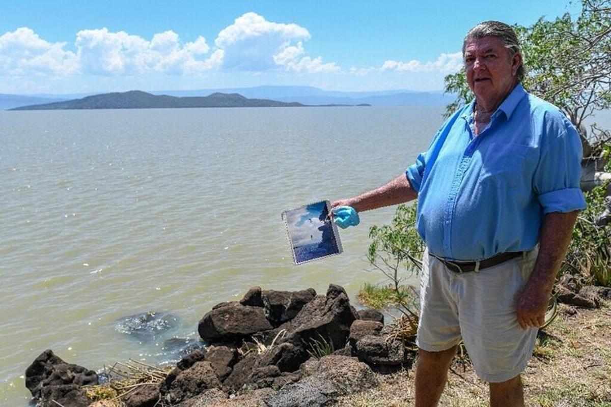 un uomo in piedi accanto a uno specchio d'acqua