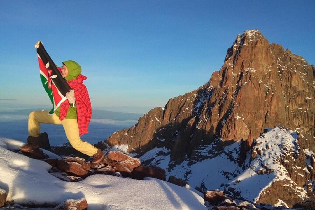 un bărbat care stă pe vârful unui munte cu o placă de snowboard