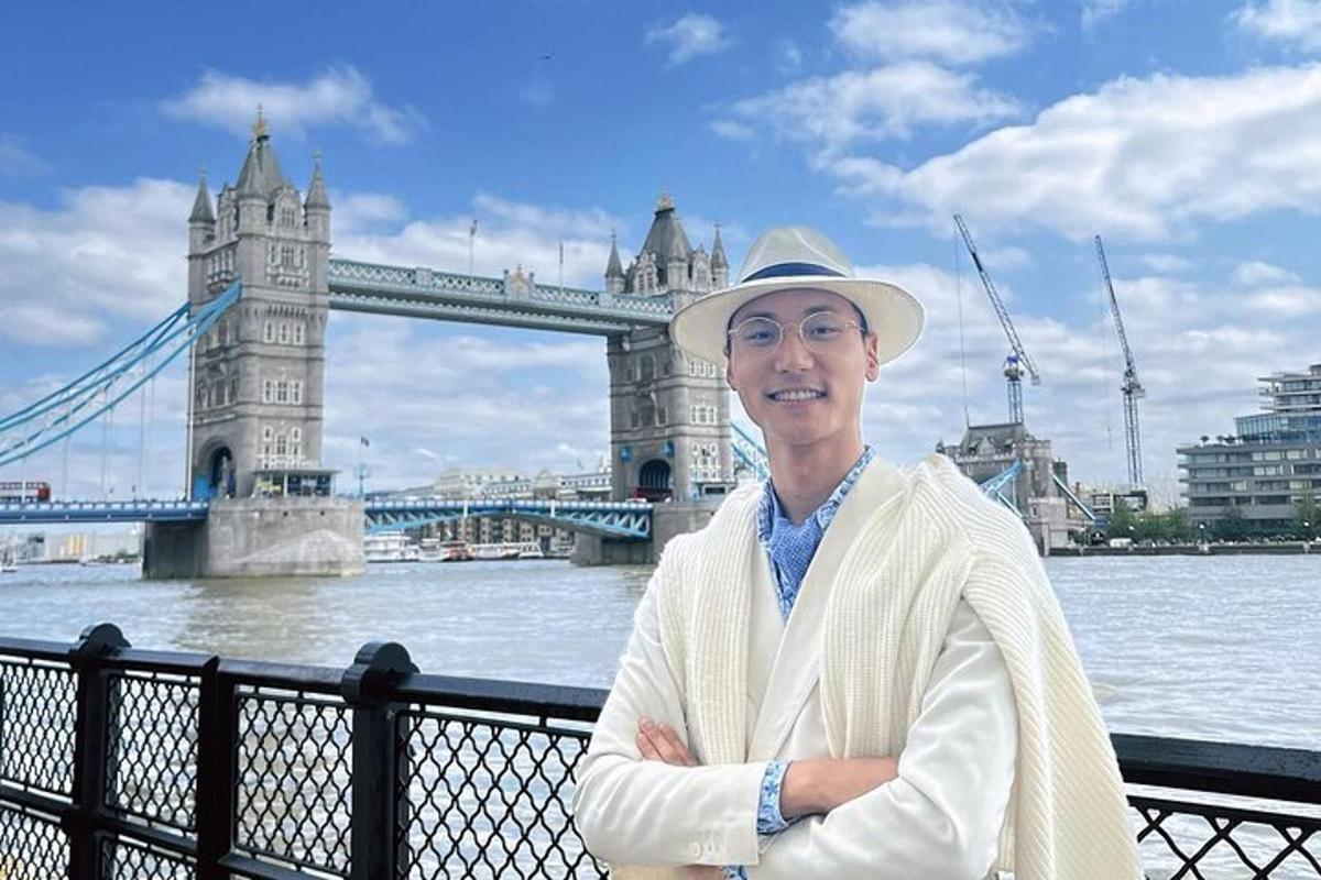 a man in a hat standing in front of a bridge