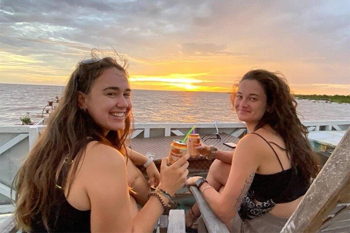 dua wanita duduk di meja di atas perahu dengan minuman
