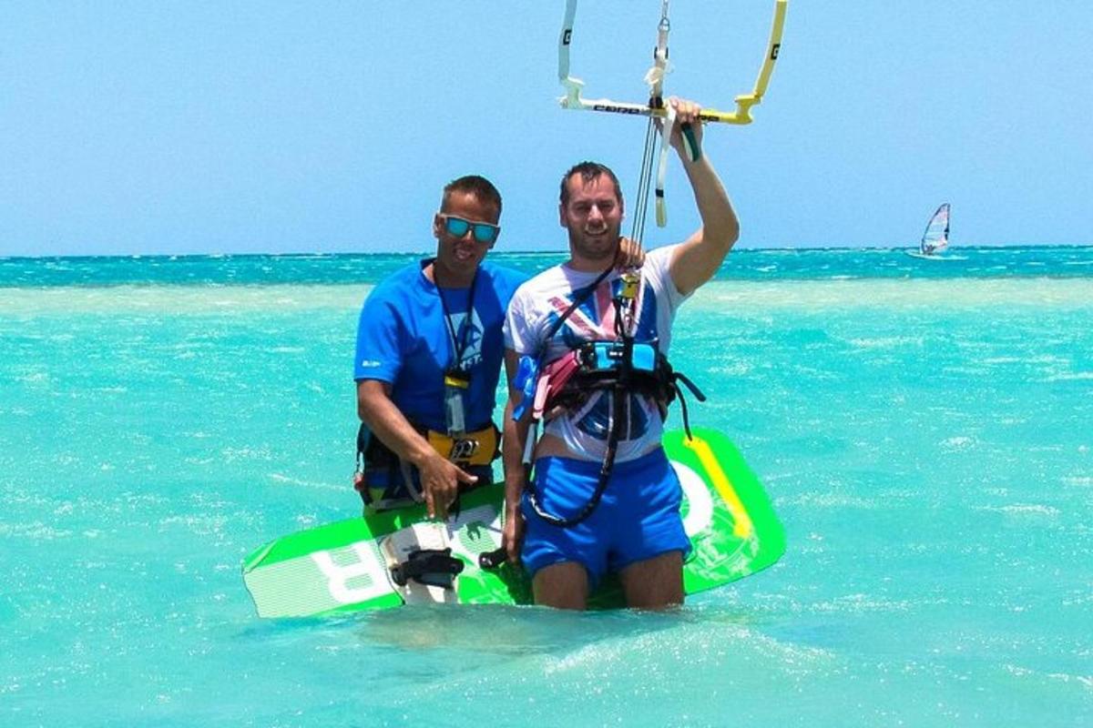 two men standing in the ocean with a paddle board