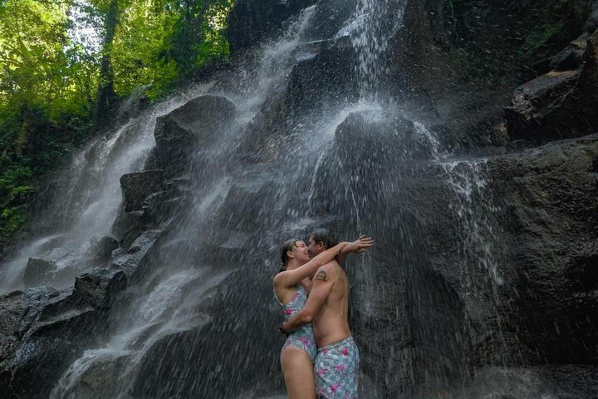 two people standing in front of a waterfall