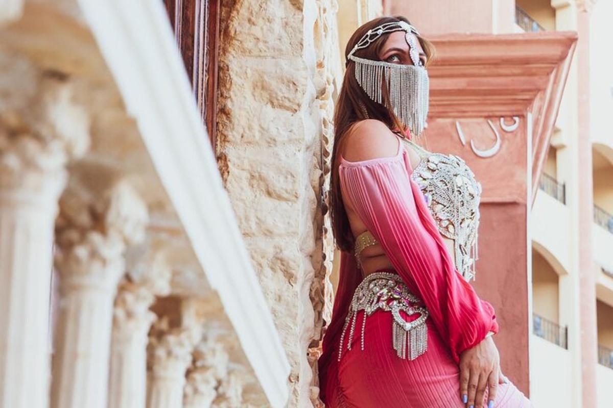 Μια γυναίκα με ροζ φόρεμα ακουμπισμένη σε ένα κτίριο
