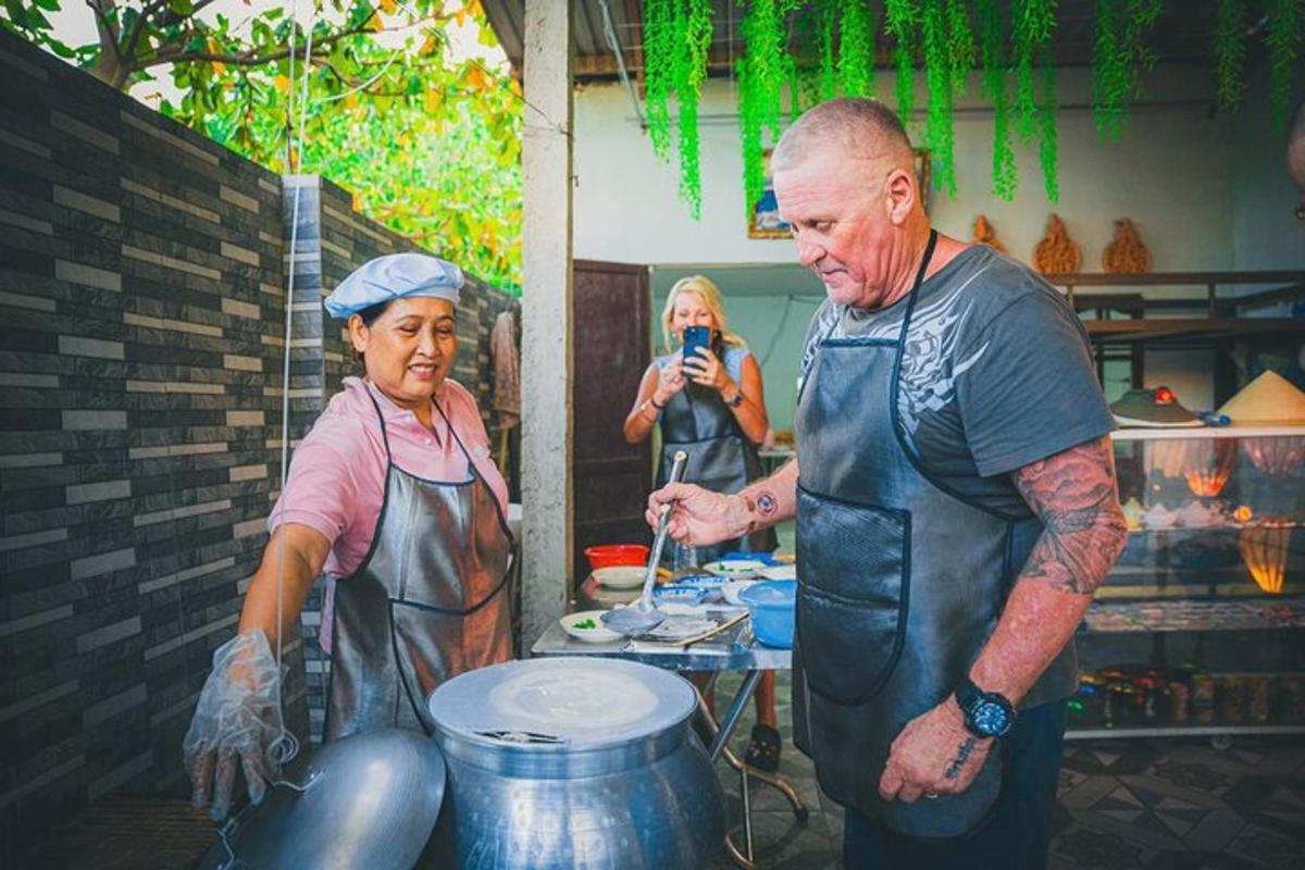 Una mujer toma una fotografía de un hombre parado junto a una mujer en una cocina.