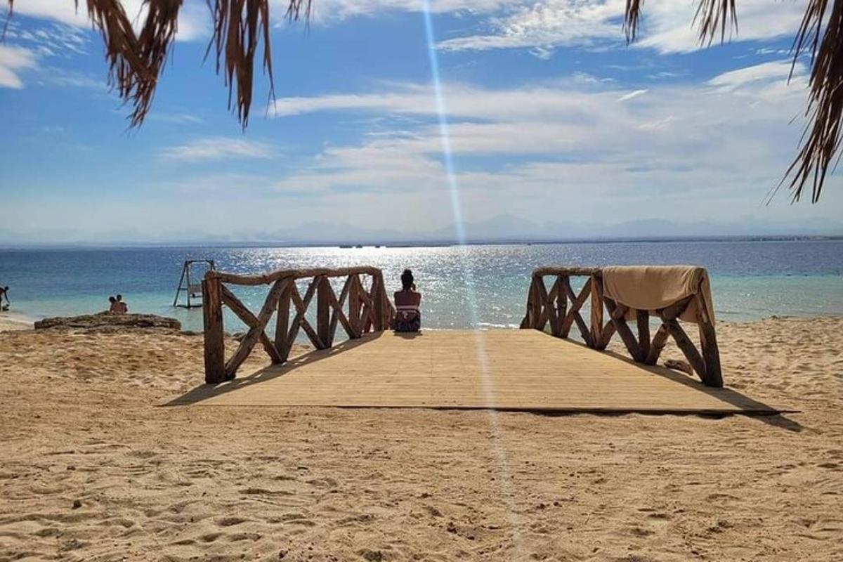 una mujer sentada en un muelle en la playa
