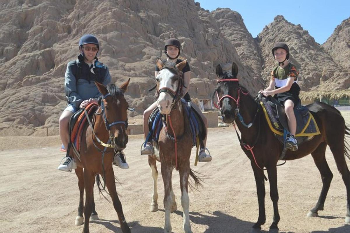 tres personas montando a caballo en el desierto