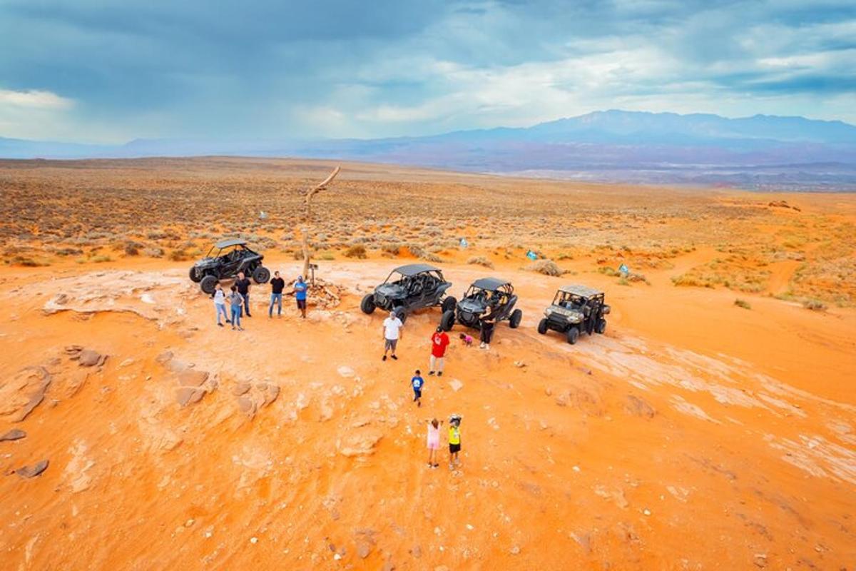 un gruppo di persone in piedi nel deserto con dei veicoli