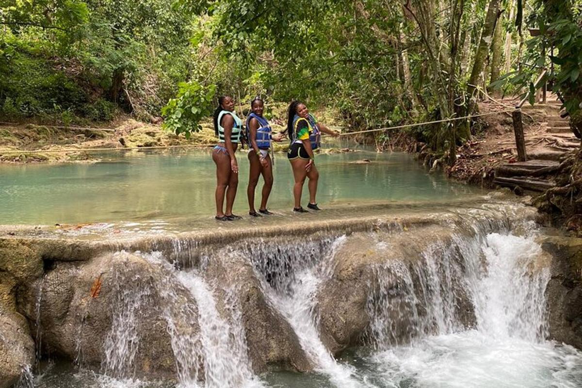 three women are standing on a bridge over a waterfall