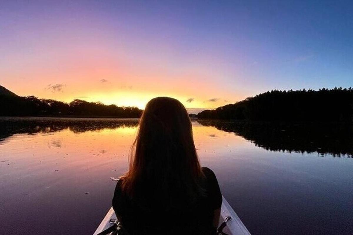 o femeie într-o barcă pe un lac la apus