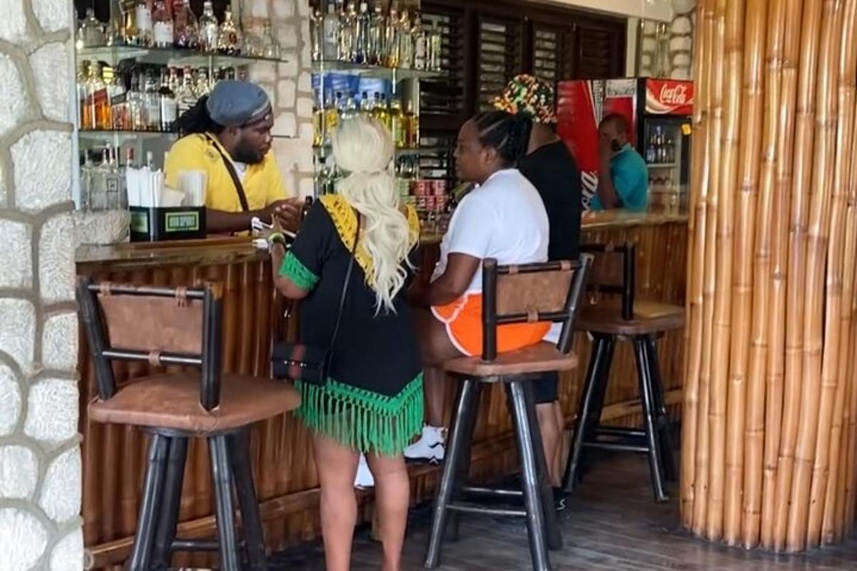 Una mujer parada en un bar con un camarero.