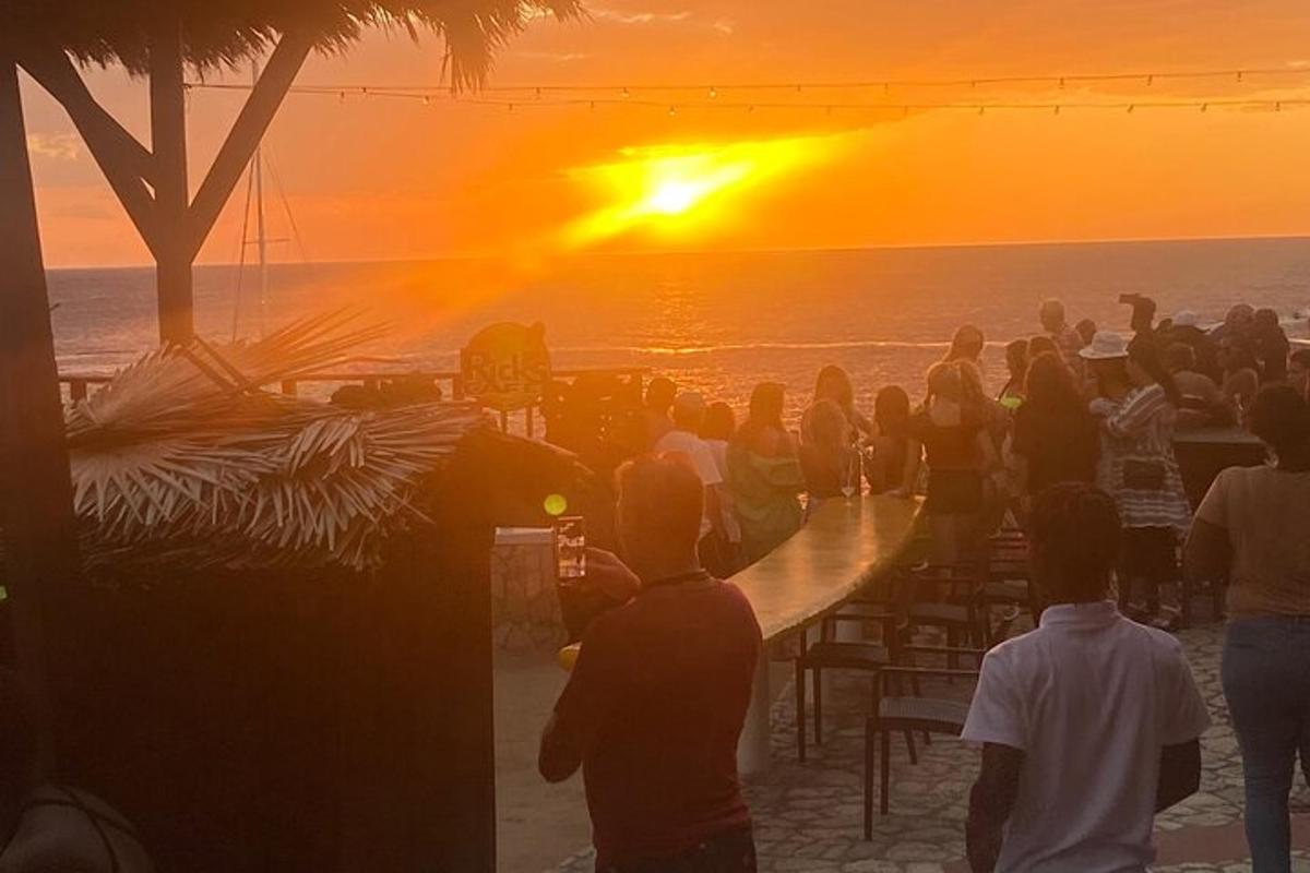 una folla di persone che guarda il tramonto sulla spiaggia