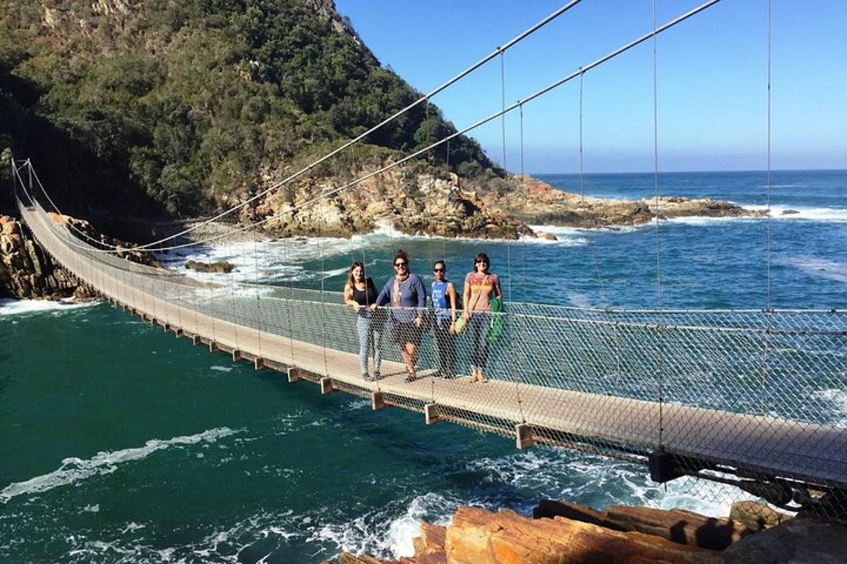 eine Gruppe von Menschen steht auf einer Hängebrücke über dem Wasser