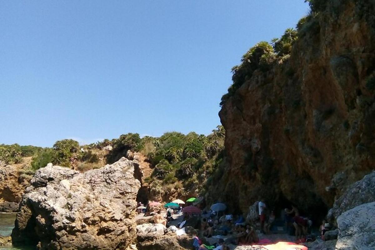 un gruppo di persone in piedi su una spiaggia accanto a una montagna