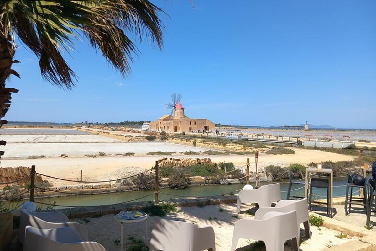 una vista di una spiaggia con sedie bianche e un mulino a vento