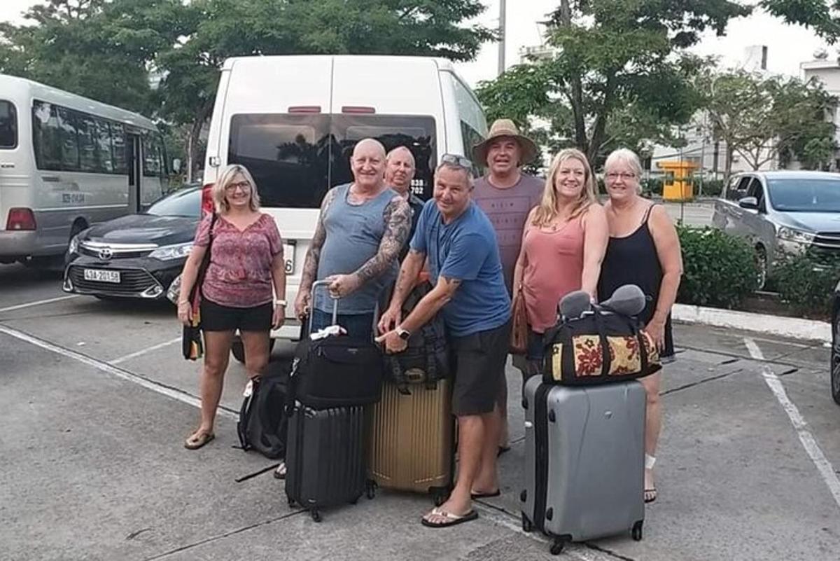 un gruppo di persone in piedi in un parcheggio con i bagagli