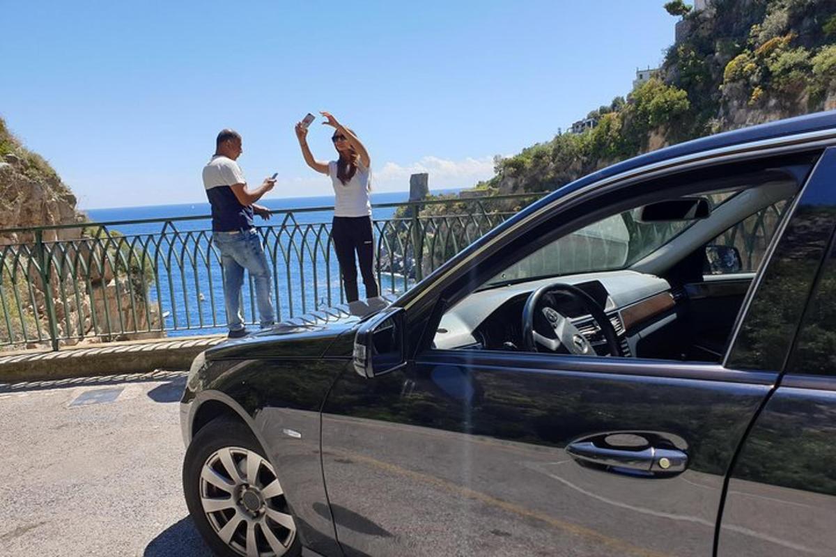 a couple of people standing on a fence near a car