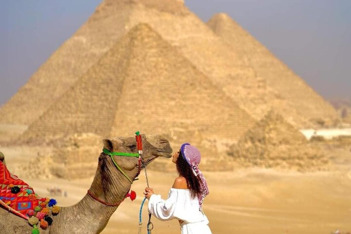 žena jedoucí na velbloudovi před pyramidami