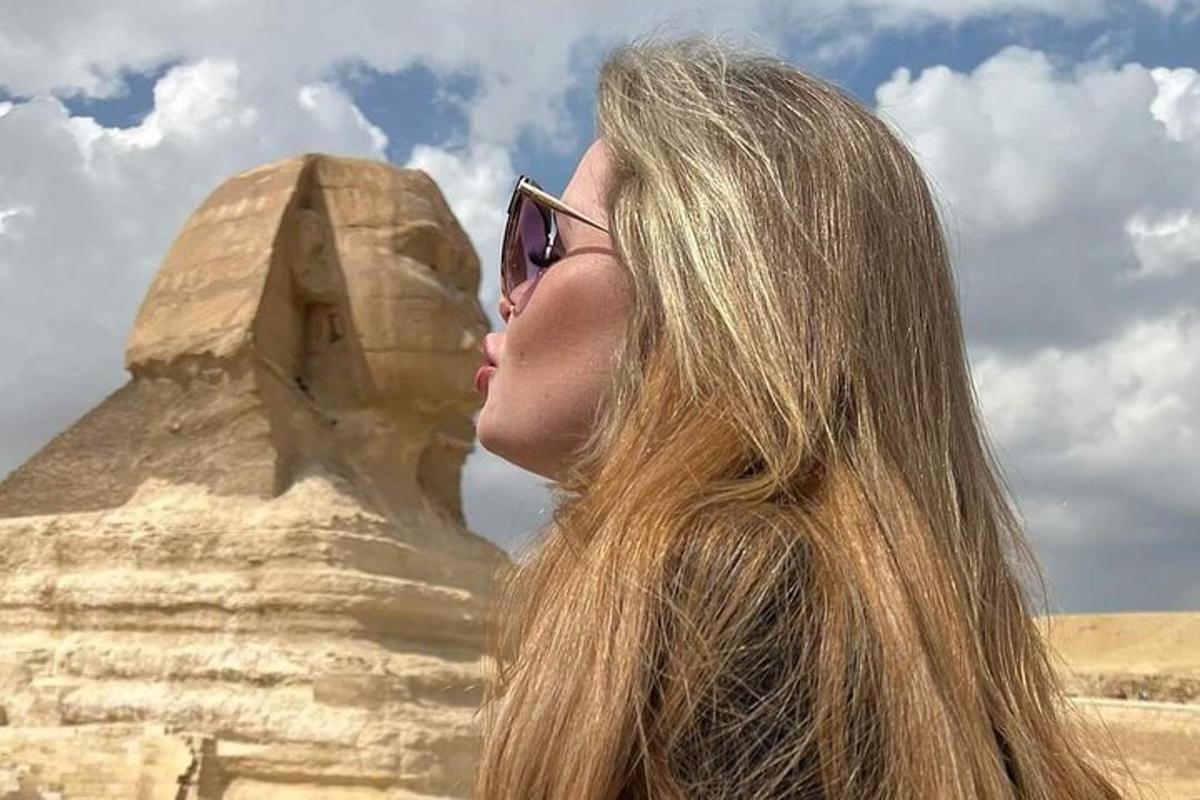 Una mujer con gafas de sol parada frente a la pirámide.